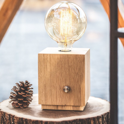 Lâmpada decorativa com base de madeira e pinha ao lado