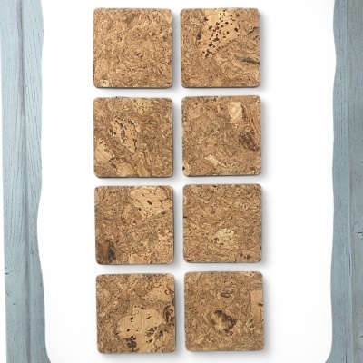 Oito pastilhas quadradas de cortiça sobre fundo branco com moldura cinza claro de madeira