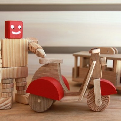 Brinquedos de madeira: boneco, mota e carruagem sobre mesa de madeira