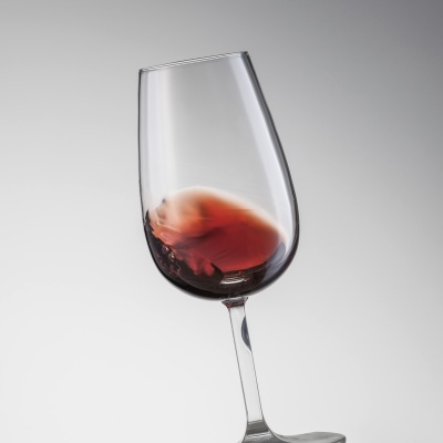 Cálice de vinho tinto agitado com fundo cinzento