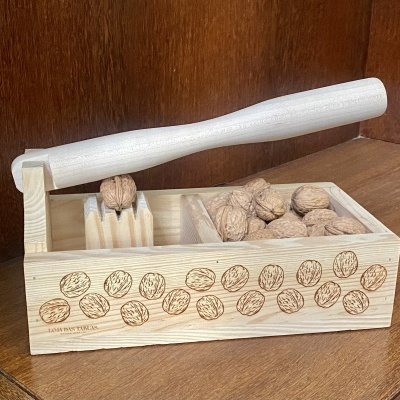 Descascador de nozes em madeira clara com ilustrações de nozes na lateral