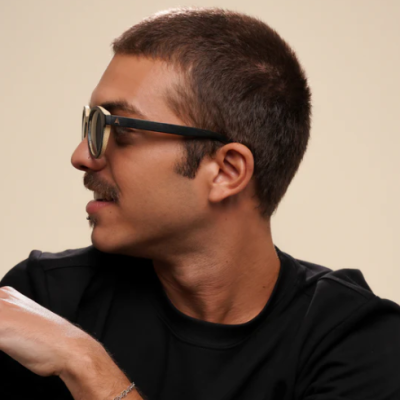 Homem de perfil com óculos de sol de armação preta e t-shirt preta