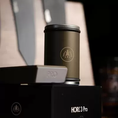 Cilindro metálico bronze com tampa cinza e logótipo de árvore, sobre caixas pretas com texto HORL 3 Pro