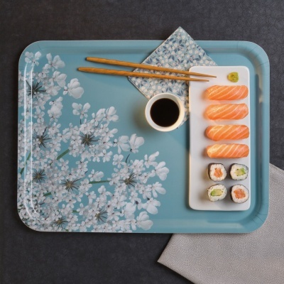 Tabuleiro azul claro com padrão floral e sushi com pauzinhos e molho.