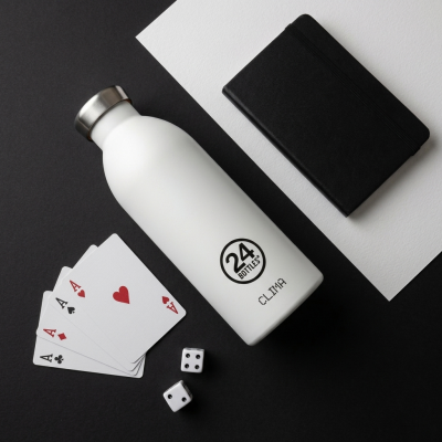 Garrafa térmica branca com tampa prateada e texto preto junto a cartas, dados e caderno
