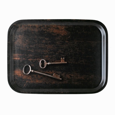 Tabuleiro preto com textura de madeira e duas chaves antigas de metal