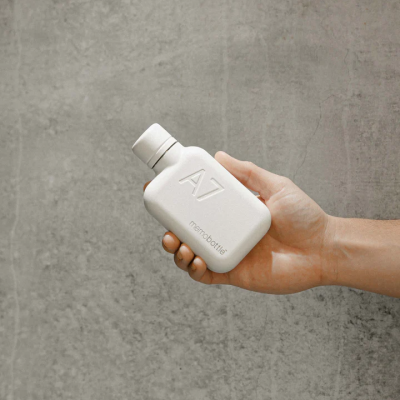 Frasco branco compacto A7 memobottle na mão com fundo cinzento