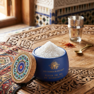 Recipiente azul com sal grosso e tampa de cortiça decorada numa mesa de madeira entalhada