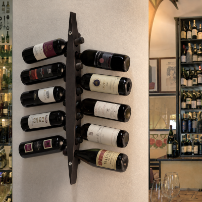 Garrafas de vinho em suporte de parede metálico com estante cheia de vinhos ao fundo