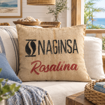 Almofada decorativa bege com texto NAGINSA Rosalina num sofá com almofadas azul e bege