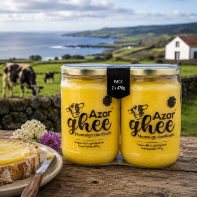 Pack de dois frascos de manteiga clarificada Azor Ghee sobre mesa com pão, vacas e paisagem verde ao fundo