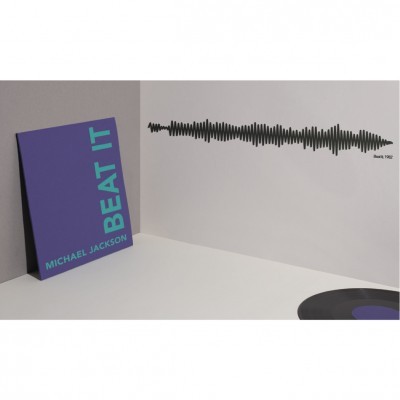 Capa de vinil Michael Jackson Beat It e vinil preto sobre mesa branca com decoração de forma de onda sonora na parede.