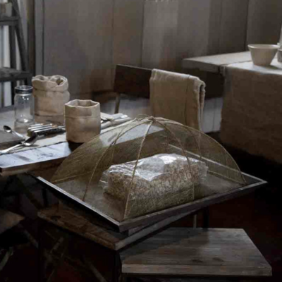 Mesa de madeira com tampa de malha fina para alimentos e acessórios de jantar em tons bege