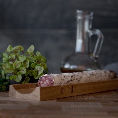 Salame branco numa tábua de madeira com planta verde e garrafa de vidro