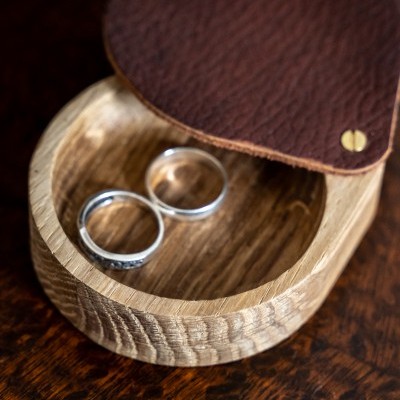 Anéis prateados numa caixa de madeira com tampa de couro castanho.