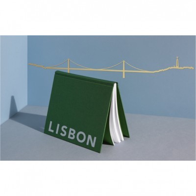 Livro ou caderno verde com texto LISBON e fundo com desenho de ponte e farol