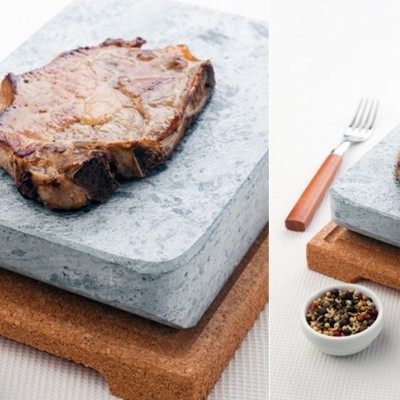 Bife sobre pedra de granito com base de cortiça e garfo ao lado