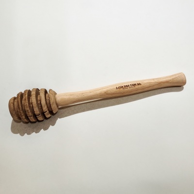 Colher de mel de madeira com inscrições sobre fundo branco.