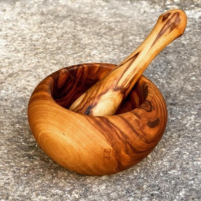 Mortar e pilão de madeira com veios naturais sobre superfície áspera.