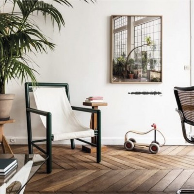 sala com cadeira preta e branca, planta em vaso, brinquedo de madeira e espelho na parede