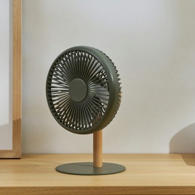 Ventoinha de secretária verde com base de madeira numa prateleira ao lado de livros e recipiente de vidro