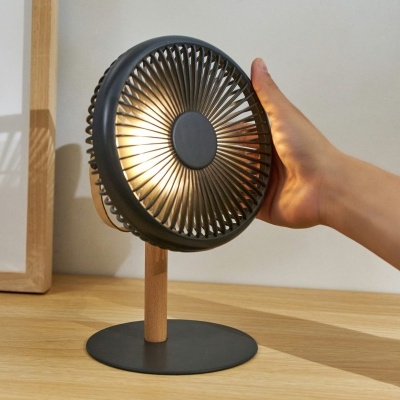 Ventoinha pequena de mesa em preto com suporte de madeira numa mesa de madeira clara