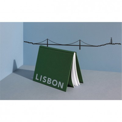 Caderno verde com texto LISBON e fundo azul com desenho de ponte