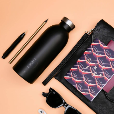 Conjunto de acessórios com garrafa preta, caneta, lápis, óculos, carteira e caderno colorido