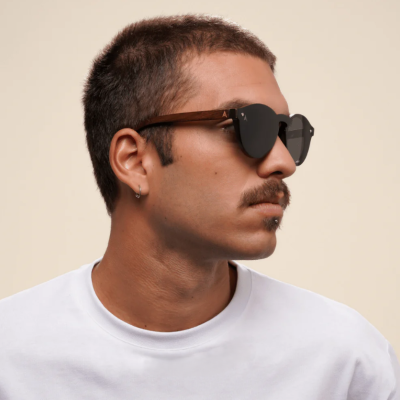 Homem a usar óculos de sol com armação de madeira castanha e lentes pretas
