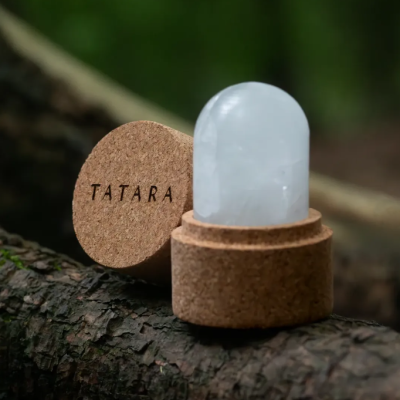Produto de cortiça TATARA com peça branca transparente, sobre madeira em fundo verde