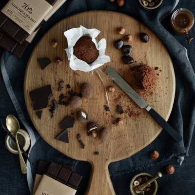 Barras de chocolate Ultra Dark e Hazelnut com elementos de confeitaria sobre tábua de madeira