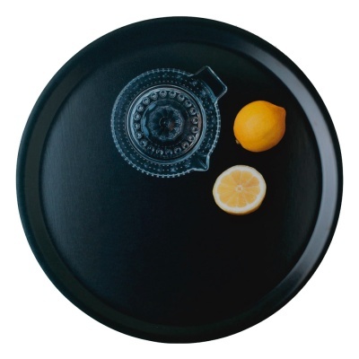 Tabuleiro preto redondo com espremedor de limão de vidro e dois limões