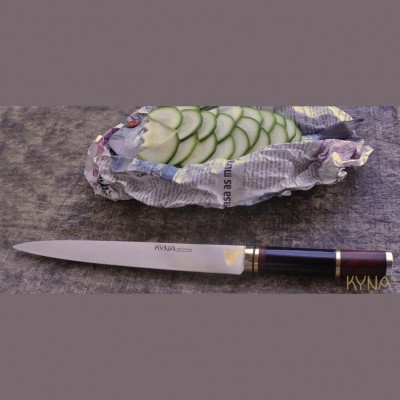 Faca de cozinha e alimento fatiado embrulhado em jornal sobre superfície cinzenta