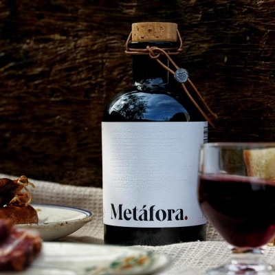 Garrafa de vinho Metáfora com rolha de cortiça e etiqueta branca numa mesa com copo de vinho e cogumelos