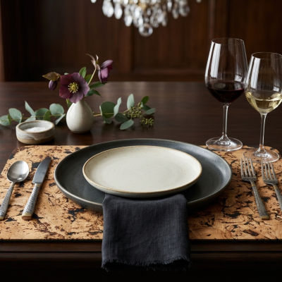 Conjunto de jantar com pratos, talheres, copos, vaso e sal sobre placemat texturizado
