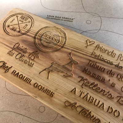Tábuas de madeira claras gravadas com texto em português e inglês e imagem de veado.