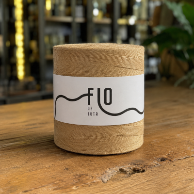 Novelo de fio de juta castanho claro com etiqueta branca em mesa de madeira