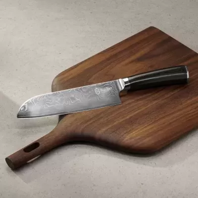Faca de chef em aço damasco com cabo preto sobre tábua de madeira escura