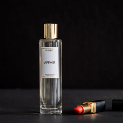 Frasco de perfume AFFAIR e batom vermelho sobre fundo preto