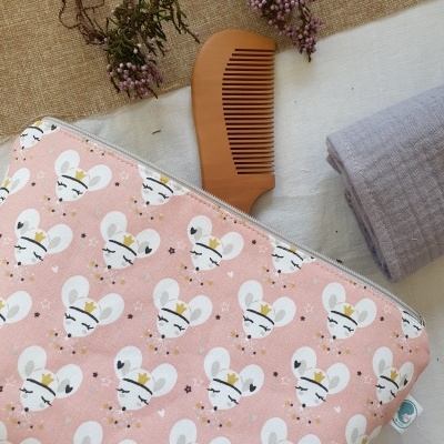 Saco rosa com padrão de ratinhos brancos, pente de madeira castanha, tecido cinzento e flores secas