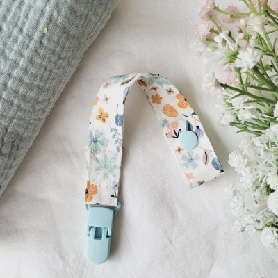 Clipe de tecido com padrão floral azul, laranja e bege sobre tecido branco