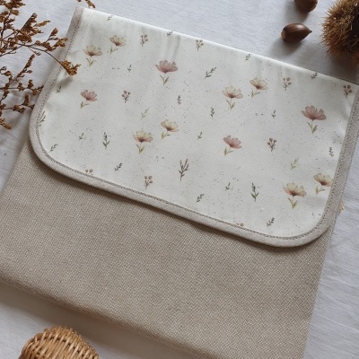 Bolsa bege e branca com padrão floral e elementos naturais ao redor