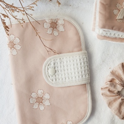 Capa cor-de-rosa com flores brancas e botão branco, scrunchie rosa e tecido floral em fundo branco