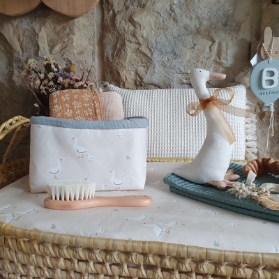 Carrinho de bebé forrado com tecido branco com patos, escova de cabelo, estojo e boneco de peluche de pato