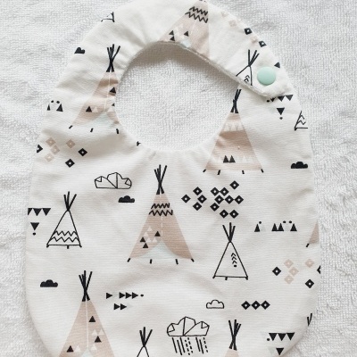 Babete de tecido com padrão de tendas em bege, preto e branco