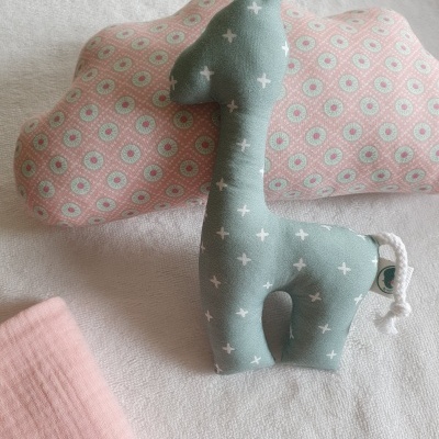 Brinquedo de peluche girafa azul com padrão de cruzes e almofada em forma de nuvem estampada