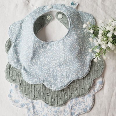 Três babetes florais para bebé com fecho de mola e formato de pétalas.