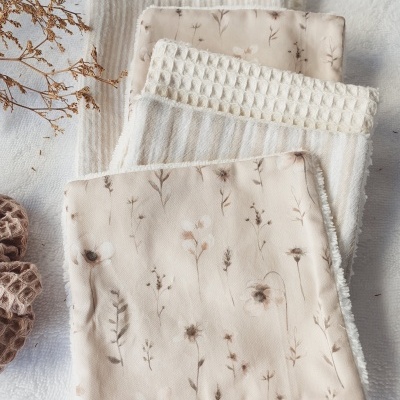 Toalhas de tecido neutras e florais com textura em malha e ramo seco ao lado