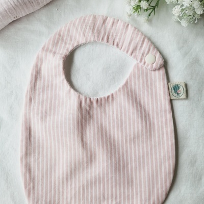 Babete de tecido rosa com riscas brancas e fecho de pressão