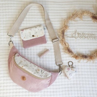 Conjunto de mala de ombro, porta-moedas, glitter labial, porta-chaves floral e moldura decorativa com a palavra 'dream'.